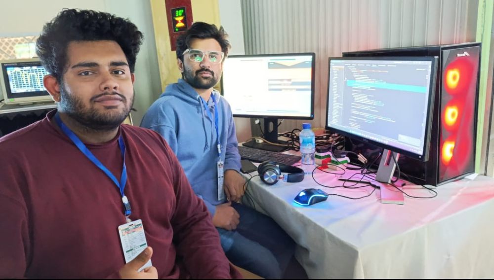 Two Chrio engineers at the workstation that runs the match, monitors showing the live pipeline